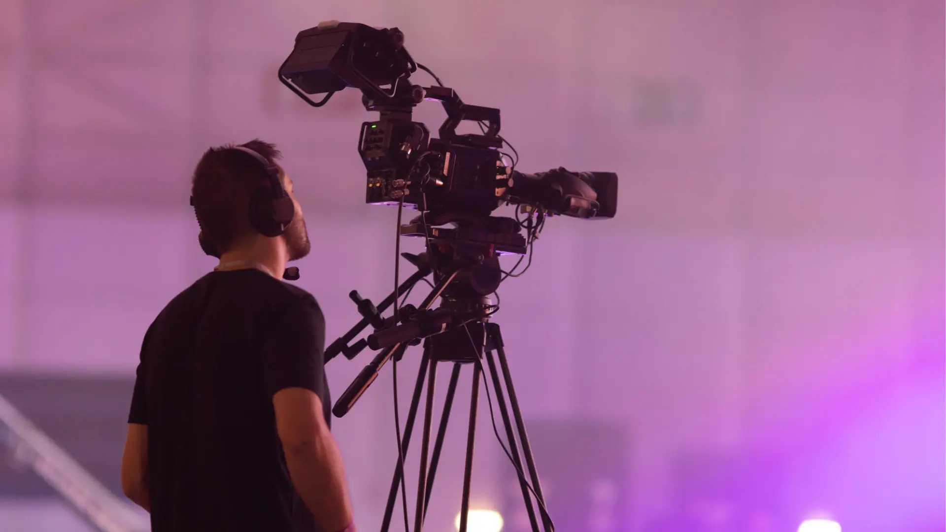Rear view of a cameraman operating a cinema-grade tripod setup for a professional media production in Pakistan.